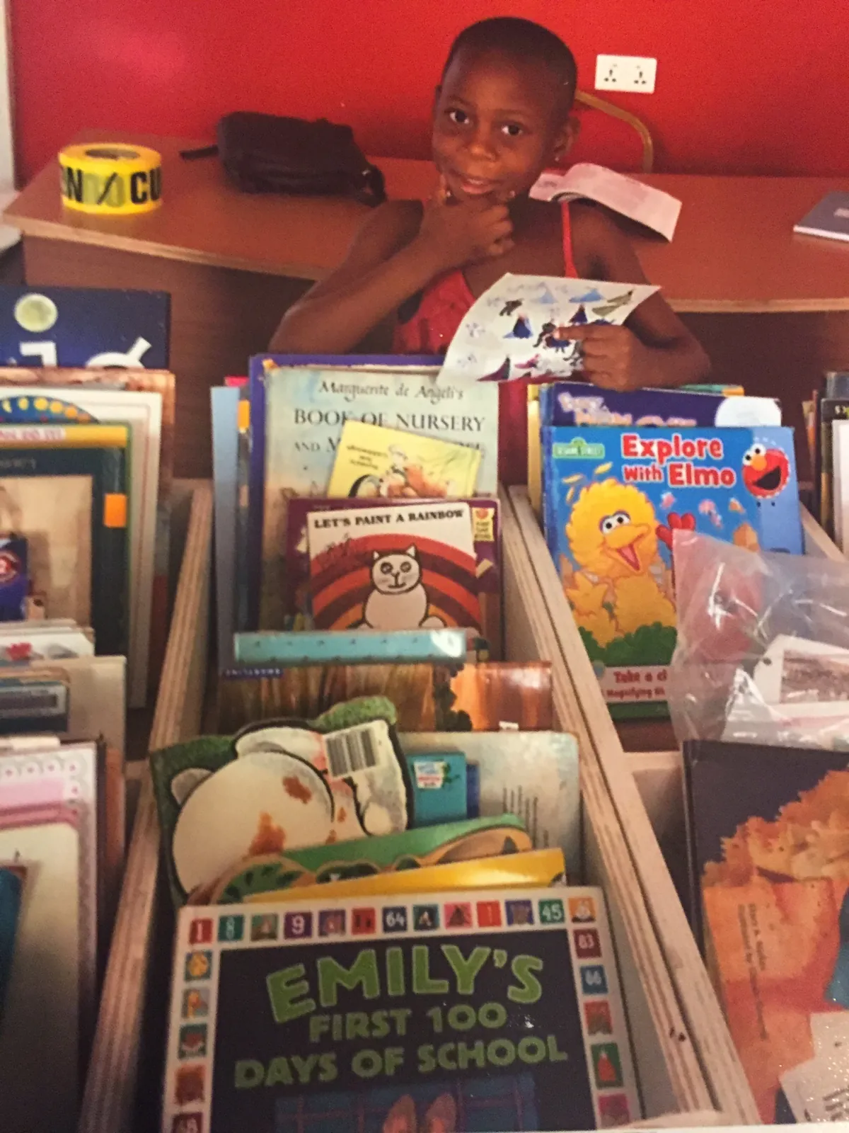 A boy smiling behind a bin of picture books