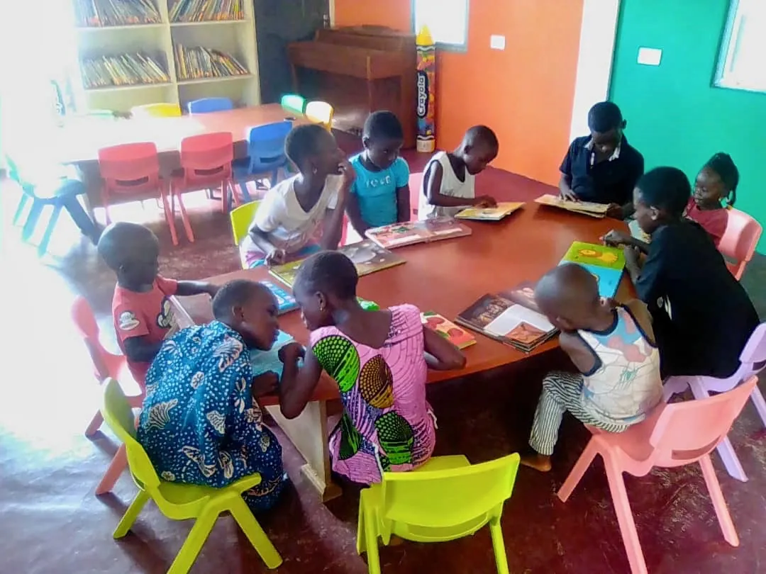 Children reading books together around a table at the Mankoadze Children's Library
