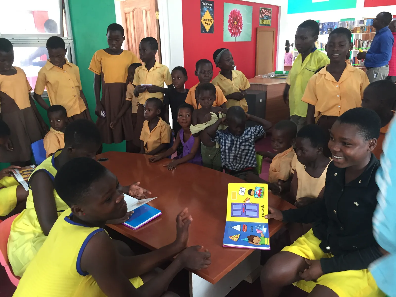 Children gathered around a table sharing a picture book