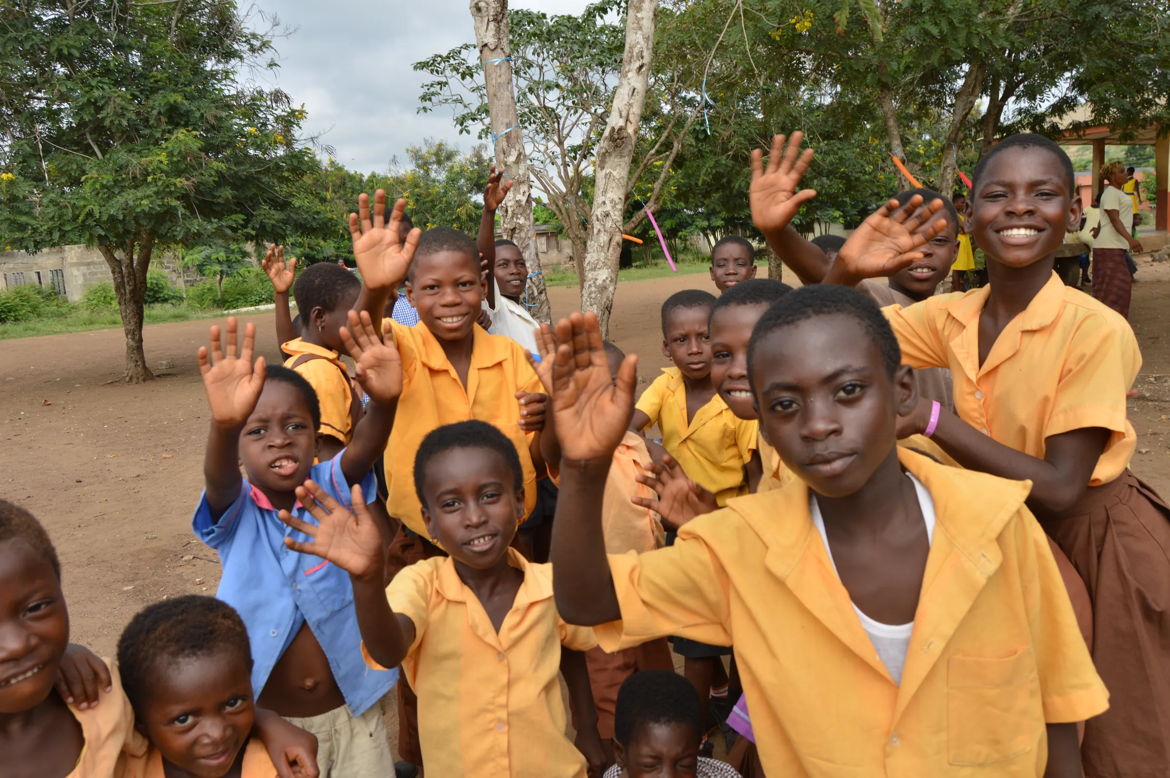 Smiling schoolchildren in uniform waving at the camera