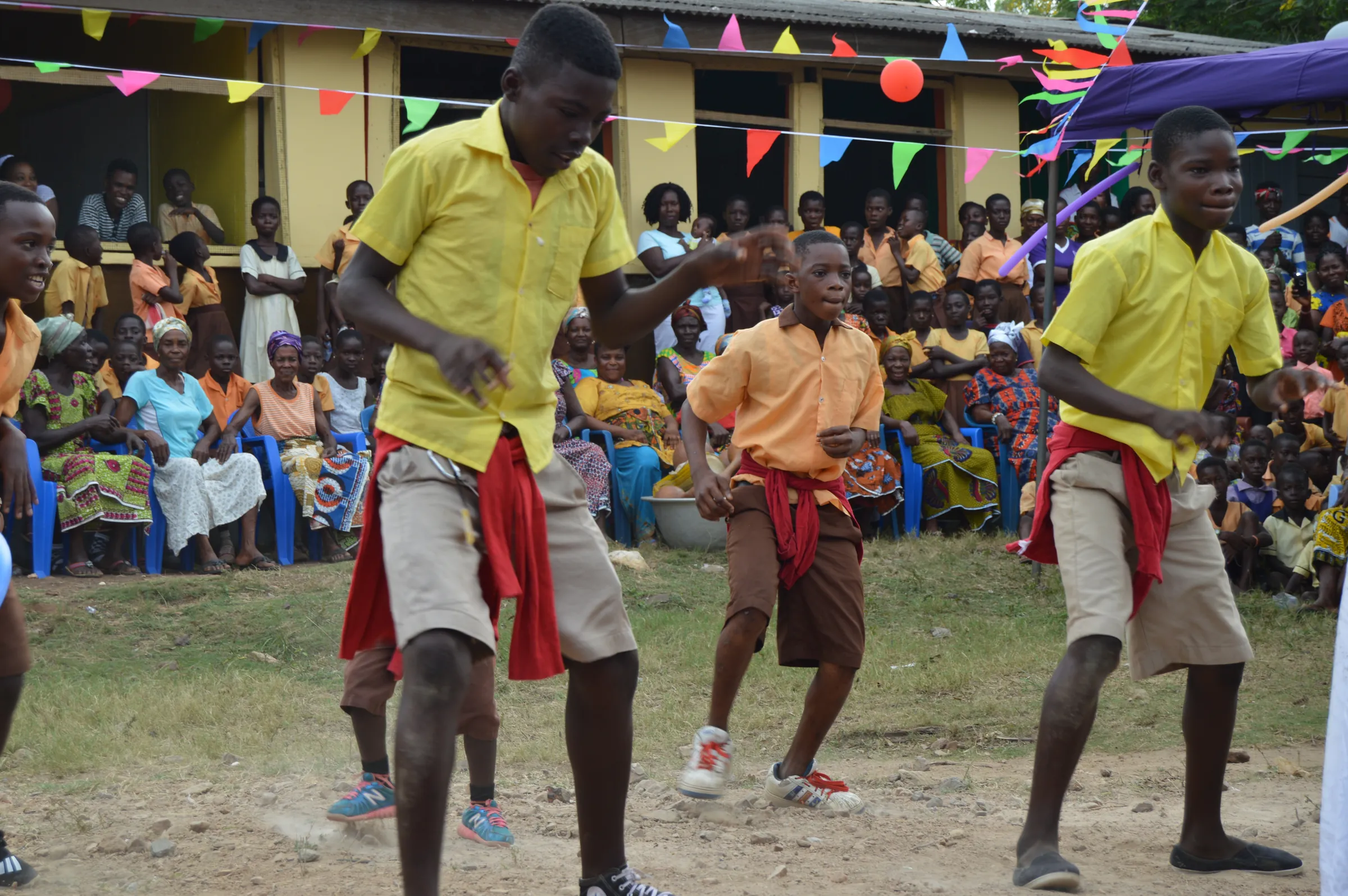 Students dancing in front of a seated crowd at a community celebration